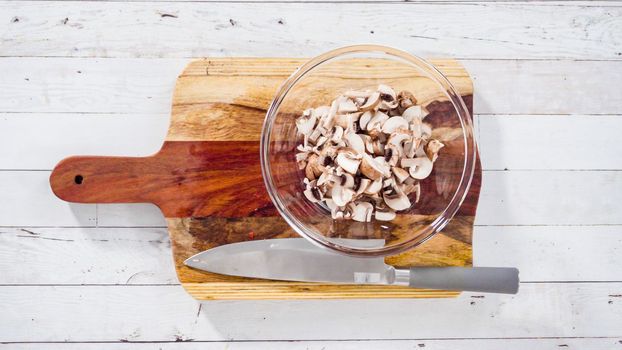 Flat lay. Cutting organic Bella mushrooms on a wood cutting board.