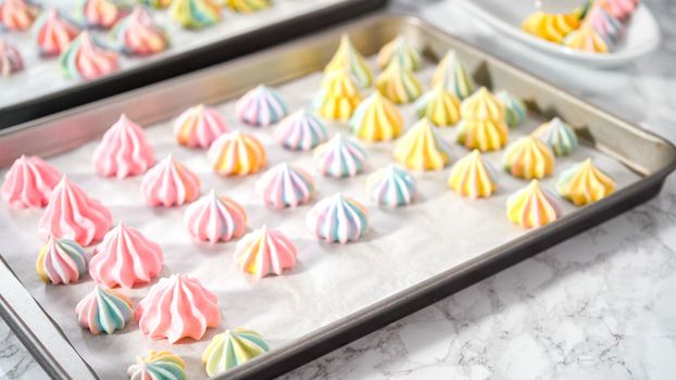 Step by step. Freshly baked unicorn meringue cookies on a baking sheet with a parchment paper.
