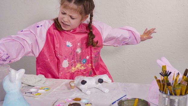 Little girl painting paper mache figurine at homeschooling art class.
