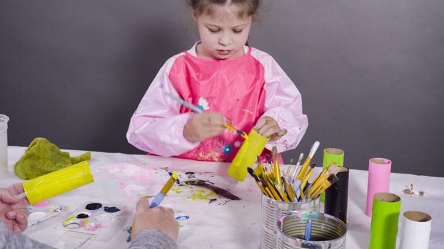 Kids papercraft. Painting empty toilet paper rolls with acrylic paint to create paper bugs.