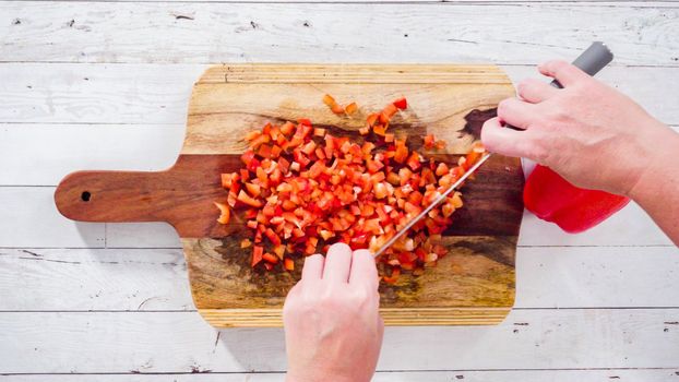 Flat lay. Mincing organic red bell peppers on a wood cutting board.