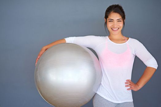 Exercise is my natural high. a sporty young woman holding a pilates ball against a grey background