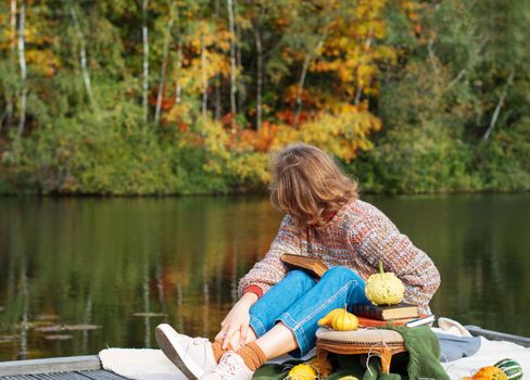 beautiful red-haired girl observes enjoys beautiful autumn nature sitting on a raft near a forest lake. High quality photo