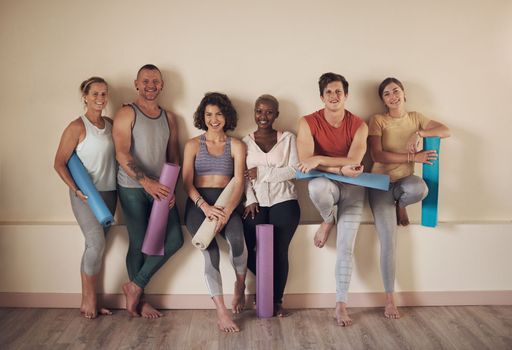 What a great yoga class. Full length portrait of a diverse group of yogis sitting together and bonding after an indoor yoga session