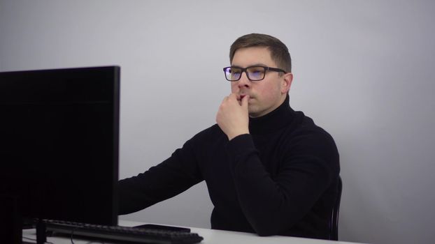 Young IT specialist works at the computer typing on the keyboard. A man with glasses sits in the office at the workplace. 4k