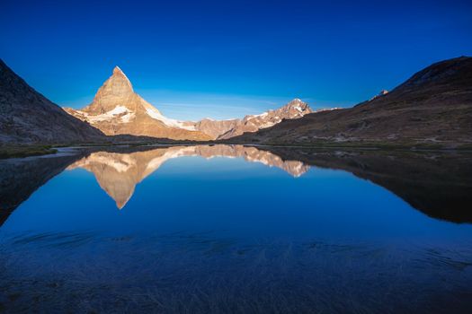 Reflection of the Matterhorn on blue and placid lake at sunrise, Swiss Alps, Zermatt, Switzerland