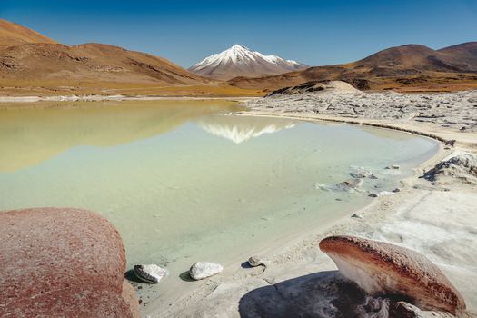 Salt lake reflection and idyllic volcanic landscape at sunrise, Atacama desert, Chile border with Bolivia