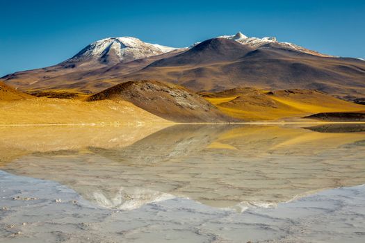 Salt lake reflection and idyllic volcanic landscape at sunrise, Atacama desert, Chile border with Bolivia