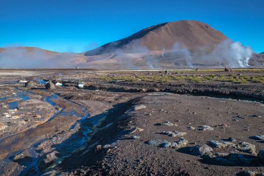 Geysers El Tatio with river and Peaceful dramatic volcanic landscape at sunrise, Atacama Desert, Chile