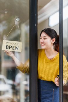 Beautiful female manager in restaurant with tablet. Woman coffee shop owner with open sign. Small business concept.