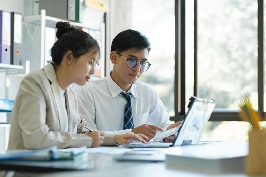 Businesspeople or colleagues are working together on investment project, discussing, sharing ideas, planning, and analyzing the business strategy and finance using laptop and graphs at workplace.