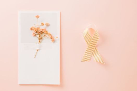 Pink awareness ribbon sign and paper card flower of World Cancer Day on pink background with copy space, concept of medical and health care support, Breast cancer awareness concept, 4 February