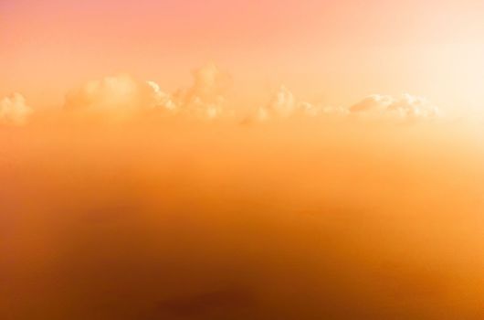 A red burning sunset with the silhouette of a cliff over the sea. Abstract nature summer or spring ocean sea background. Small waves on golden warm water surface with bokeh lights from sun.
