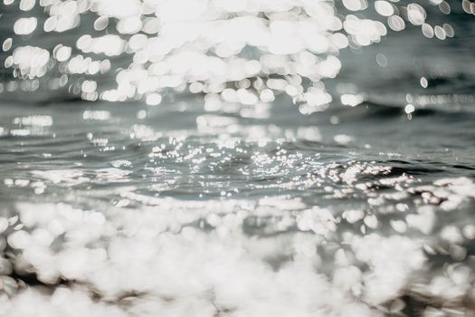 Abstract sea summer ocean sunset nature background. Sound of small waves on golden water surface in motion blur with golden bokeh lights from sun. Holiday, vacation and recreational concept.