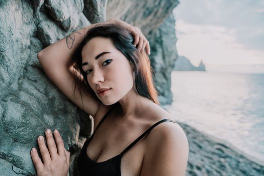 Portrait of cheerful female climber ascending a rock. The athlete girl trains in nature. Woman overcomes difficult climbing route.