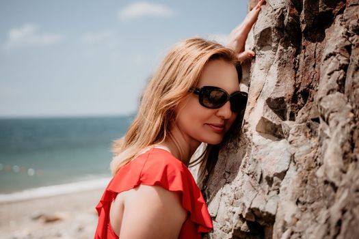 Young woman in red bikini on Beach. Blonde in sunglasses on pebble beach enjoying sun. Happy lady in one piece red swimsuit relaxing and sunbathing by turquoise sea ocean on hot summer day. Close up,