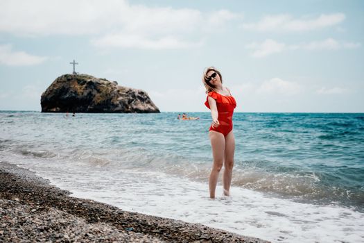 Young happy woman walks carefree on the seaside. Happy lady in red bikini. Portrait beautiful young woman relax smile around beach sea ocean in holiday vacation travel trip.