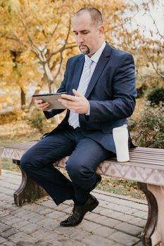 Mature entrepreneur drink coffee in autumn park. Senior executive rest in city park.
