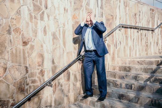 Portrait of a senior professional man in a suit with various problems. A middle-aged businessman with a briefcase descends the stairs.