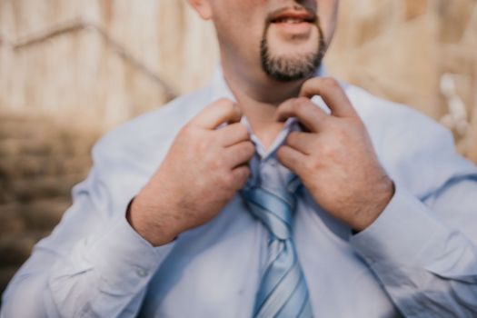 Close up of Man Adjusting Tie of Suit. Businessman in white shirt straightens his tie, close-up.