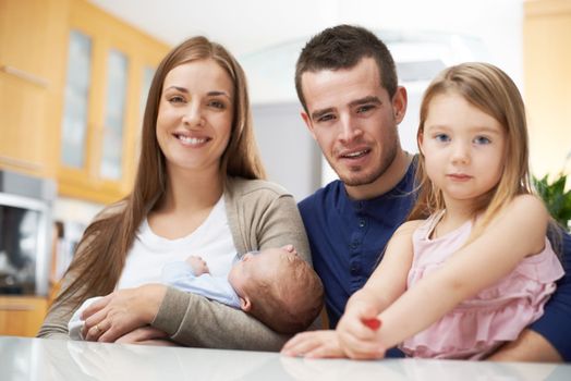 Family time is so important. A young family in their kitchen and looking at the camera