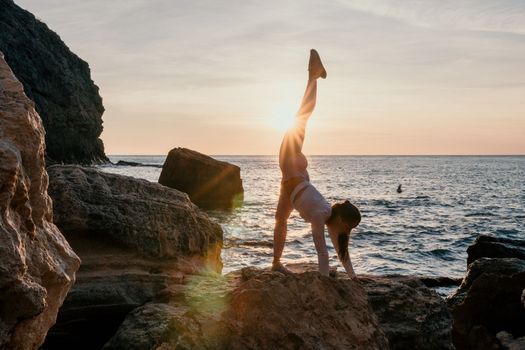 Young woman with black hair, fitness instructor in pink sports leggings and tops, doing pilates on yoga mat with magic pilates ring by the sea on the beach. Female fitness daily yoga concept