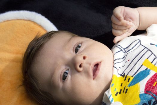 Two month old baby lying on a towel. Happy expression