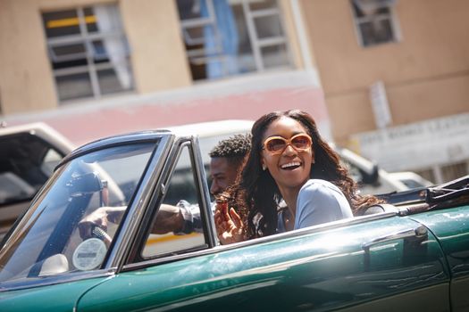 To travel is to live. A happy young couple driving in a convertible on a bright summers day