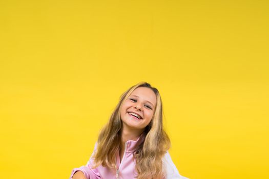 Child adorable girl hairdresser cutting long blonde hair with metallic scissors on a yellow