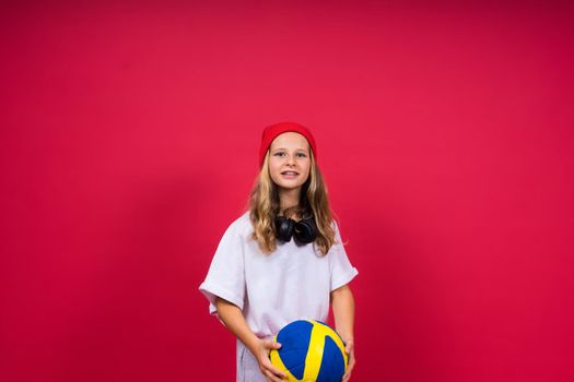 Portrait of cute eight year old girl in volleyball outfit isolated on a red background