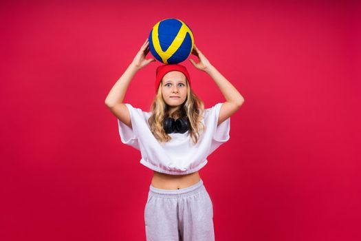 Portrait of cute eight year old girl in volleyball outfit isolated on a red background