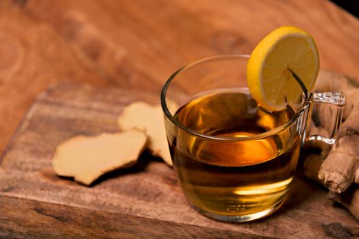 Cup of hot tea with ginger root, lemon and curcuma. Adding natural raw honey to cup of hot tea. Vitamin C drink, immune system boost