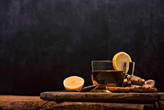Cup of hot tea with ginger root, lemon and curcuma. Adding natural raw honey to cup of hot tea. Vitamin C drink, immune system boost