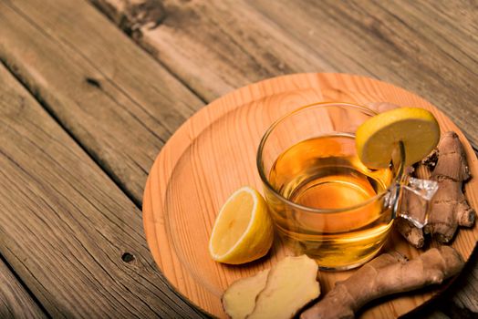 Cup of hot tea with ginger root, lemon and curcuma. Adding natural raw honey to cup of hot tea. Vitamin C drink, immune system boost