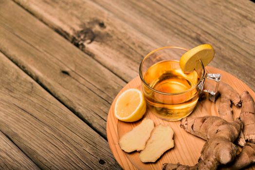 Cup of hot tea with ginger root, lemon and curcuma. Adding natural raw honey to cup of hot tea. Vitamin C drink, immune system boost