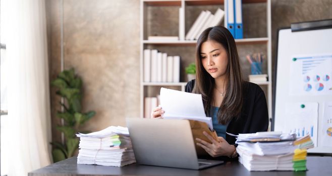 Young Asian businesswoman working on laptop computer, stressed has a headache and thinks hard from work at the office...