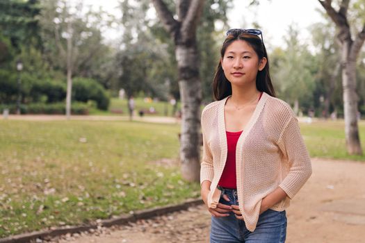 young asian woman strolling relaxed in the park, concept of youth and leisure, copy space for text