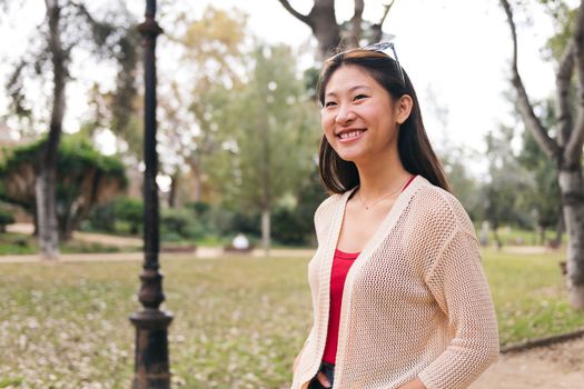 young asian woman strolling smiling in the park, concept of youth and leisure, copy space for text