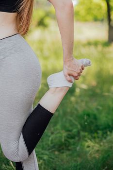 Young slim sporty woman warming and stretching legs before run outdoors at sunset or sunrise. Athletic man in black sportswear doing fitness stretching exercises. Sport and healthy lifestyle.