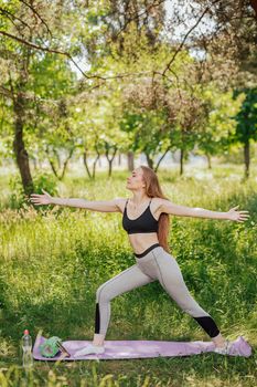 Overweight young woman is training on sports ground. An obese female does slopes outdoors. Doing sports in quarantine. Side view portrait of black lady during workout on fresh air at summer day.