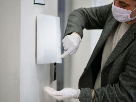 man hands in gloves Using Automatic Alcohol Dispenser to Clean Bacteria and Corona Virus. Dezinfection shopping in moll