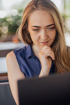 Young business woman working at a computer in a cafe. A young downshifter girl works at a laptop, working day