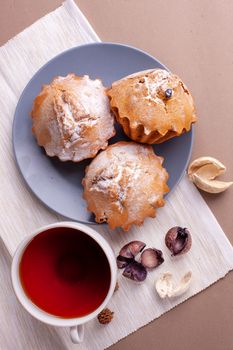 Pecan nut muffins with cup of tea on a plate. Grey background with cupcake Copy space.