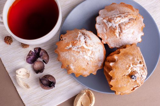 Pecan nut muffins with cup of tea on a plate. Grey background with cupcake Copy space.