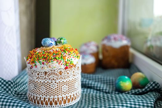 Traditional Easter cake with glace icing and Easter eggs on wooden background with willow twigs. Spring season. Orthodox Easter. Close up, selective focus