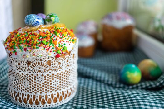 Festive cakes with white glaze, nuts and raisins with Easter eggs on the festive table. Preparations for Easter.