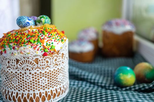 Festive cakes with white glaze, nuts and raisins with Easter eggs on the festive table. Preparations for Easter.