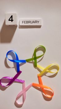 Cancer disease symbol with colored ribbons on white background close-up on world Cancer Awareness Day , vertical