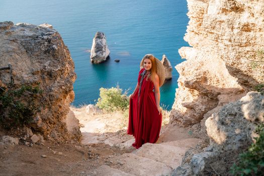 A woman in a red flying dress fluttering in the wind, against the backdrop of the sea