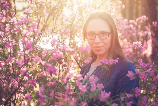 Woman travelling in Altai mountains on spring beautiful booming pink Rhododendron flowers background